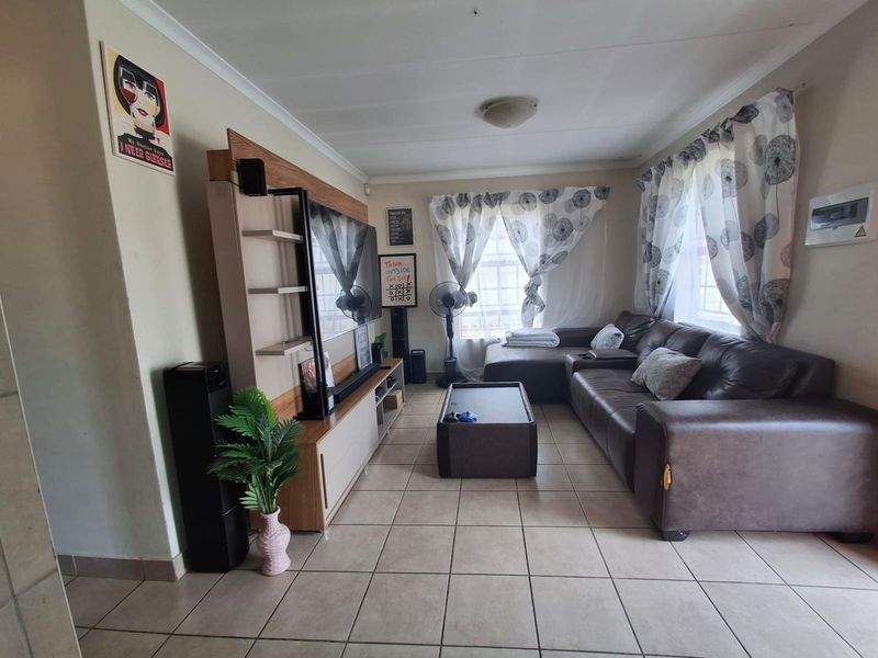 A functional living room featuring tiled flooring and coved cornicing, providing a neutral base for potential interior updates.