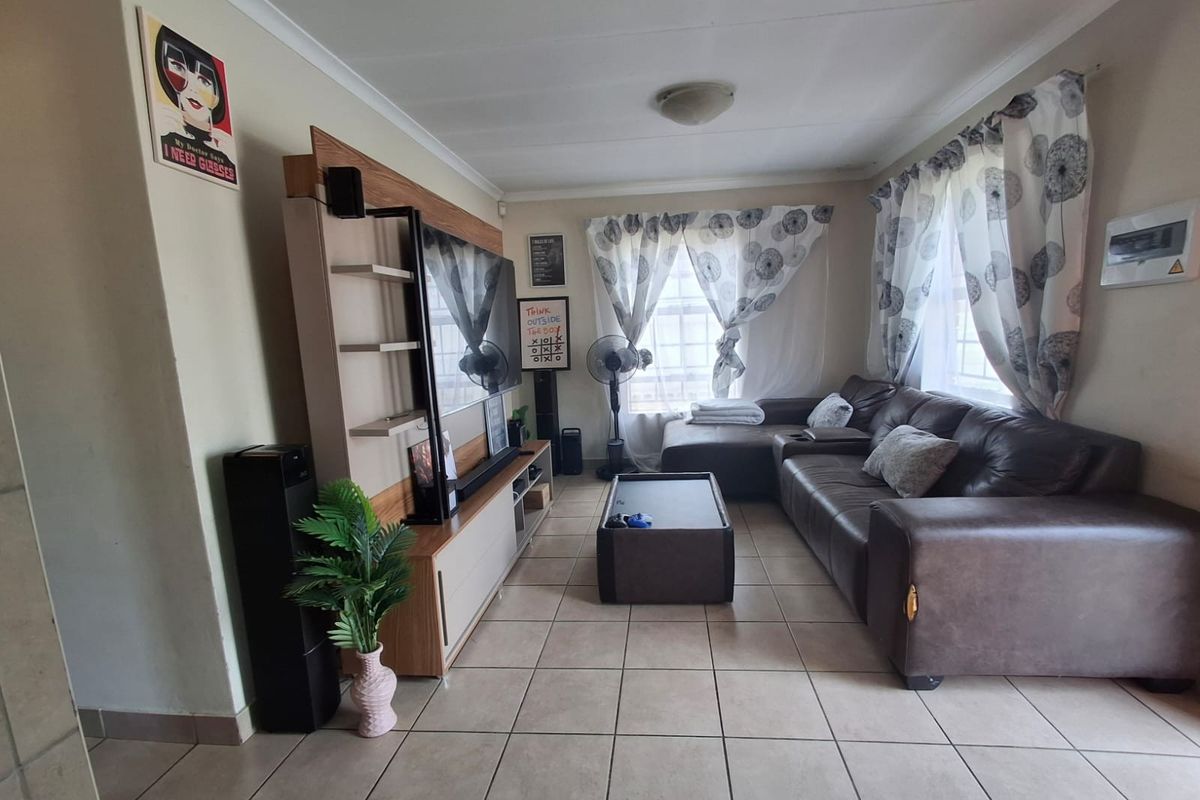 A functional living room featuring tiled flooring and coved cornicing, providing a neutral base for potential interior updates.