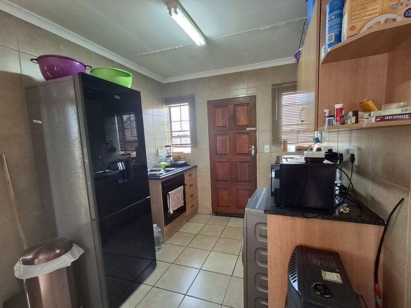 A functional kitchen featuring tiled walls and flooring, built-in cabinetry, and a built-in oven with hob, providing a practical workspace.