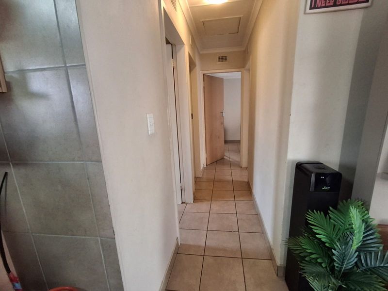 A functional hallway featuring neutral tiled flooring and access to multiple rooms, providing a clean and simple transition space within the home.