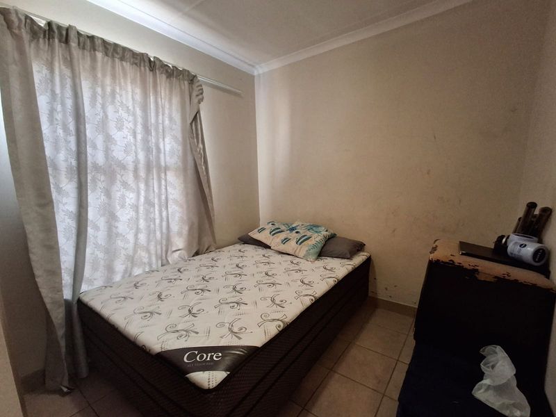 A compact bedroom featuring tiled flooring and cove cornicing, currently requiring cosmetic attention to the wall finishes.
