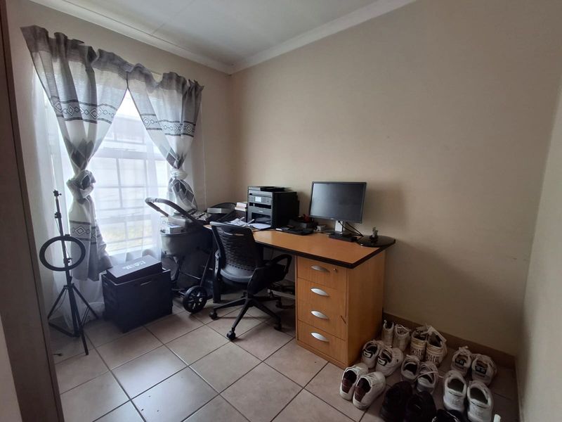 A functional office space featuring tiled flooring and a window, suitable for a home workspace or study area.