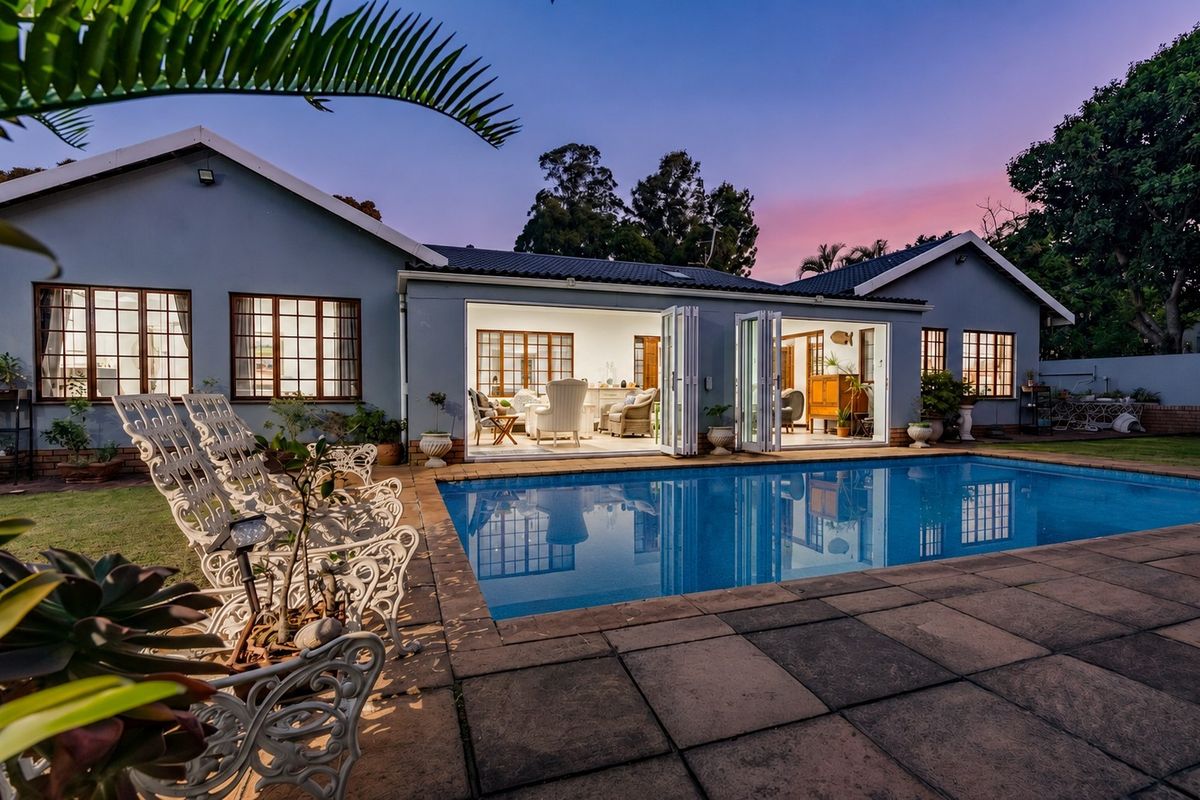 Rear exterior view of the townhouse featuring a swimming pool, paved patio area, and large bi-fold doors opening into the living space.