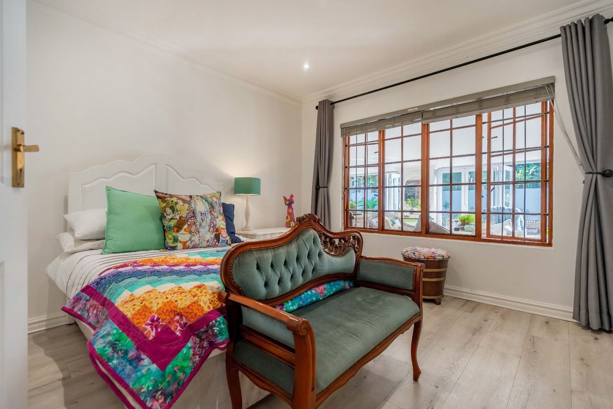 A well-maintained bedroom featuring timber-framed windows, laminate flooring, and classic cornicing, offering a bright and comfortable living space.