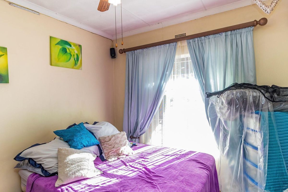 A bedroom featuring a ceiling fan, curtain rod, and window access, providing a functional space with standard finishes.
