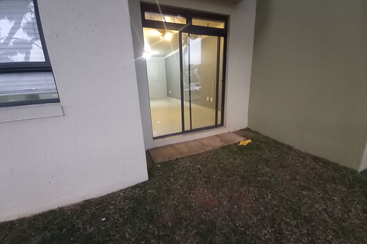 Exterior view of the apartment showing a small private garden area with sliding glass door access to the interior living space.