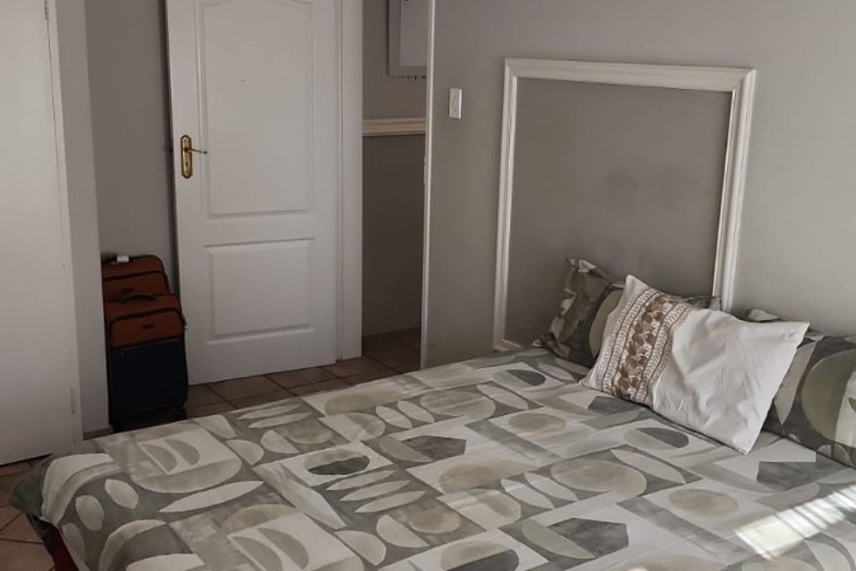 A bedroom featuring tiled flooring, built-in wardrobe storage, and recessed downlighting, providing a functional and neutral living space.