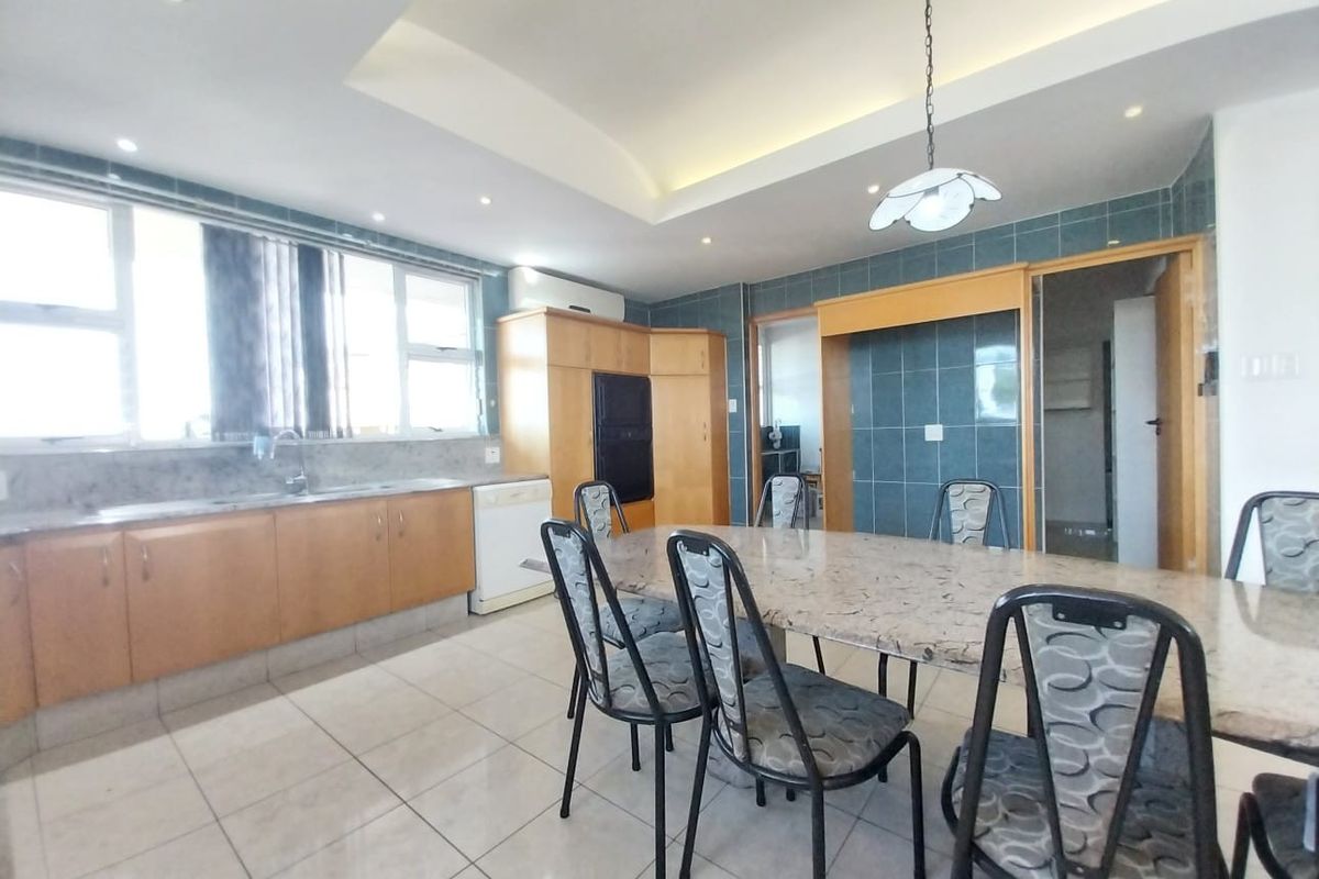 Open-plan kitchen and dining area featuring tiled flooring, built-in wooden cabinetry, and recessed ceiling lighting.