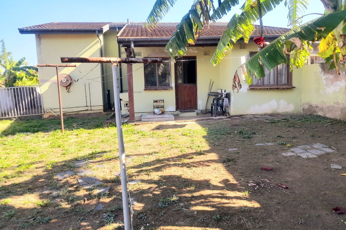Rear view of the house featuring a concrete patio area, tiled roof, and a garden space with a metal washing line.