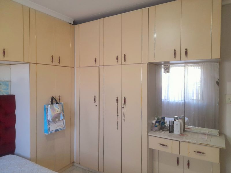 Bedroom featuring extensive floor-to-ceiling built-in cupboards with an integrated vanity unit and mirror.