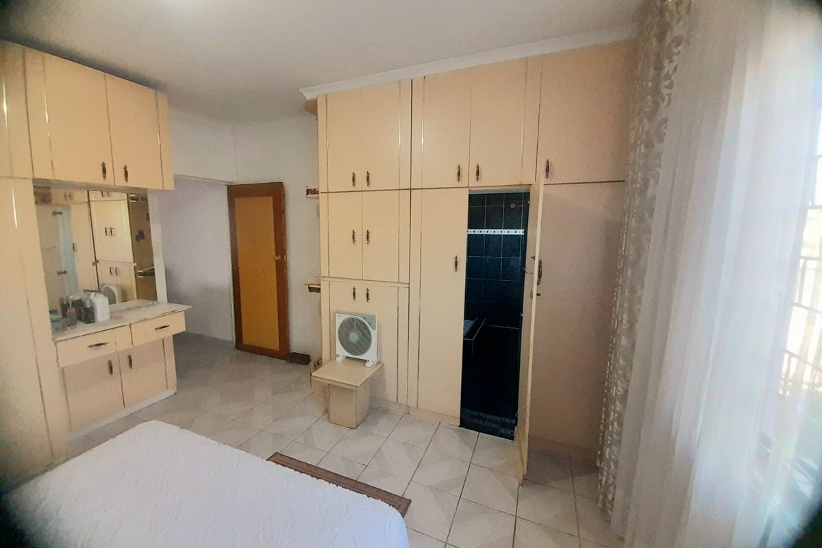 Bedroom featuring extensive built-in cabinetry, a vanity area, and tiled flooring, with direct access to an en-suite bathroom.