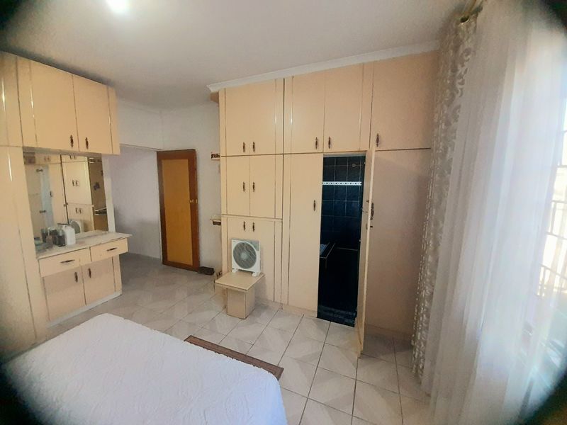 Bedroom featuring extensive built-in cabinetry, a vanity area, and tiled flooring, with direct access to an en-suite bathroom.