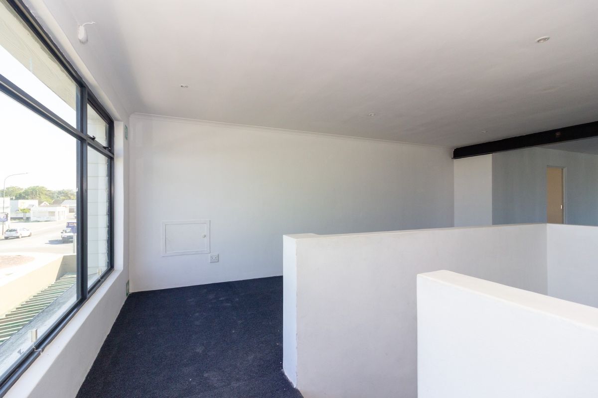 A bright, open-plan office space featuring large windows, neutral finishes, carpeted flooring, and a modern partition wall, offering a clean and professional work environment.