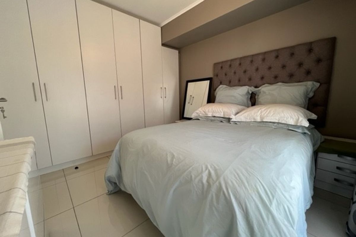 A well-maintained bedroom featuring extensive built-in floor-to-ceiling wardrobes and polished tile flooring.