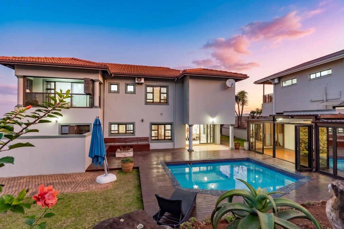 Rear view of the townhouse featuring a swimming pool, timber decking, and a covered patio area, set against a landscaped garden.