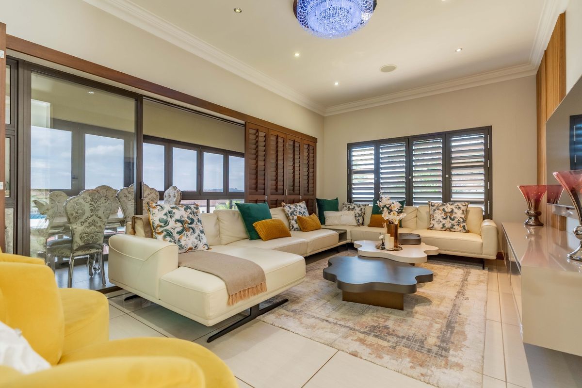 Spacious living room featuring tiled flooring, recessed lighting, crown molding, and large sliding glass doors with plantation shutters providing access to the patio.