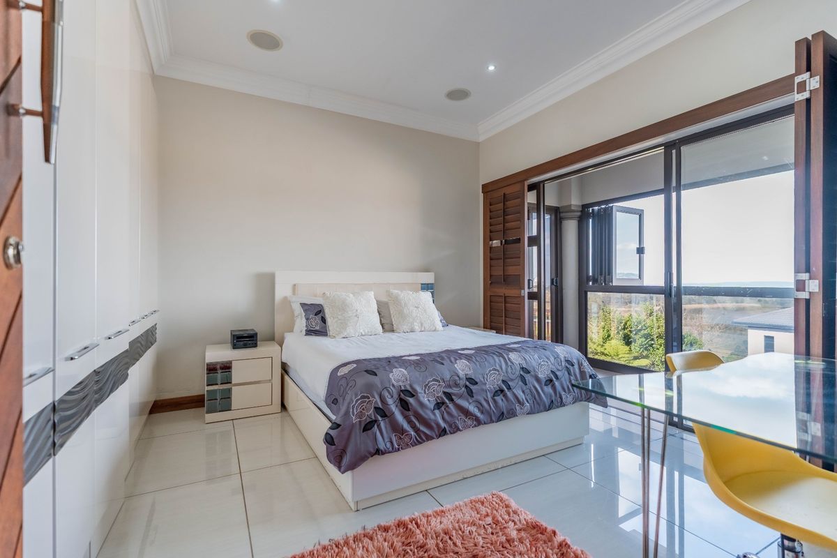 A well-maintained bedroom featuring high-gloss built-in cupboards, polished tile flooring, and large sliding glass doors that open to an outdoor balcony area.