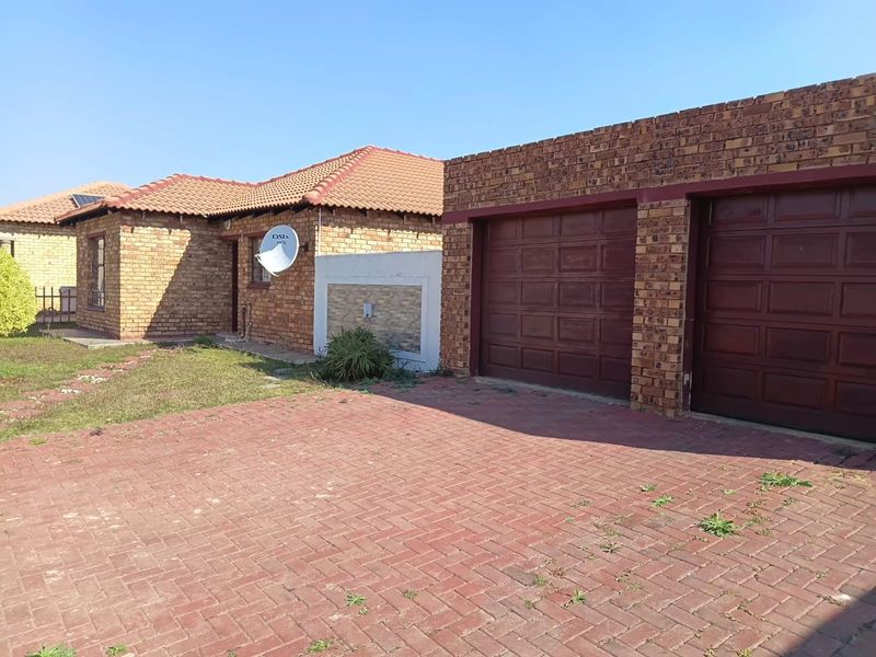 Front exterior view of a face-brick house featuring a double garage, paved driveway, and tiled roof.