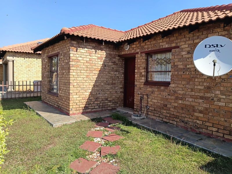 Exterior view of a face-brick house featuring a tiled roof, paved walkway, and satellite dish installation.