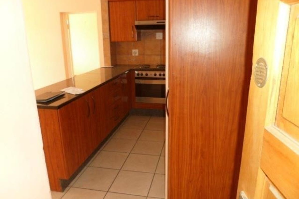 A functional kitchen featuring built-in wooden cabinetry, granite countertops, and integrated cooking appliances with tiled flooring.