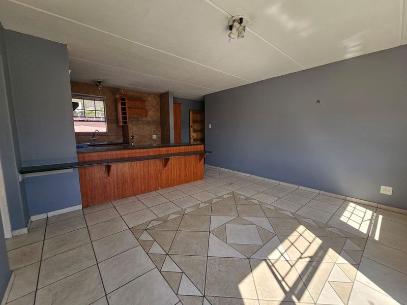 Open plan living area featuring a breakfast bar, tiled flooring with decorative inlay, and integrated kitchen cabinetry.