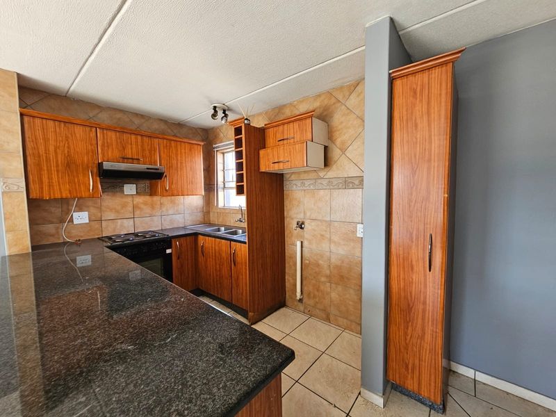 A dated kitchen featuring granite countertops, wooden cabinetry, and built-in appliances, requiring some maintenance and cosmetic updates to modernize the space.