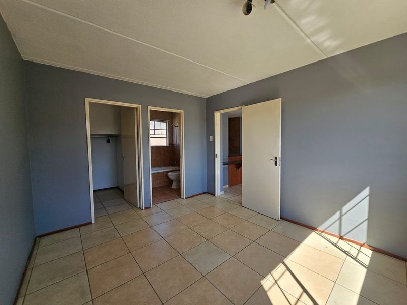 An empty bedroom featuring tiled flooring, a built-in closet, and direct access to an en-suite bathroom.