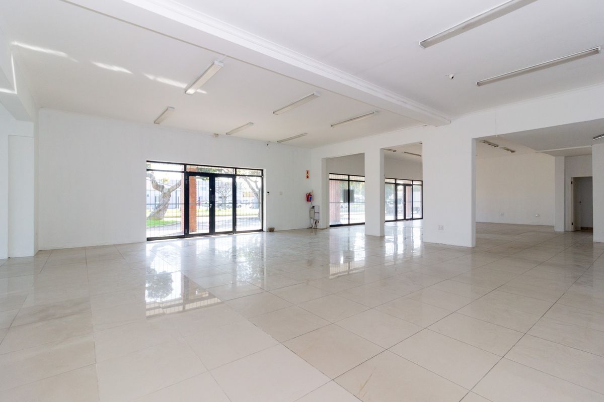 Spacious open-plan retail area featuring polished tiled flooring, ample natural light through large glass doors, and neutral white walls.