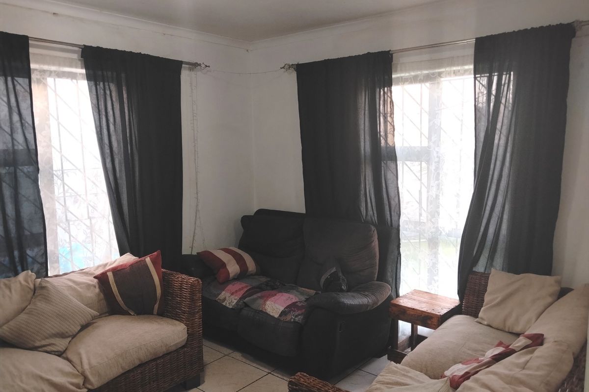 A living room featuring tiled flooring and dual windows with security bars, providing natural light to the space.