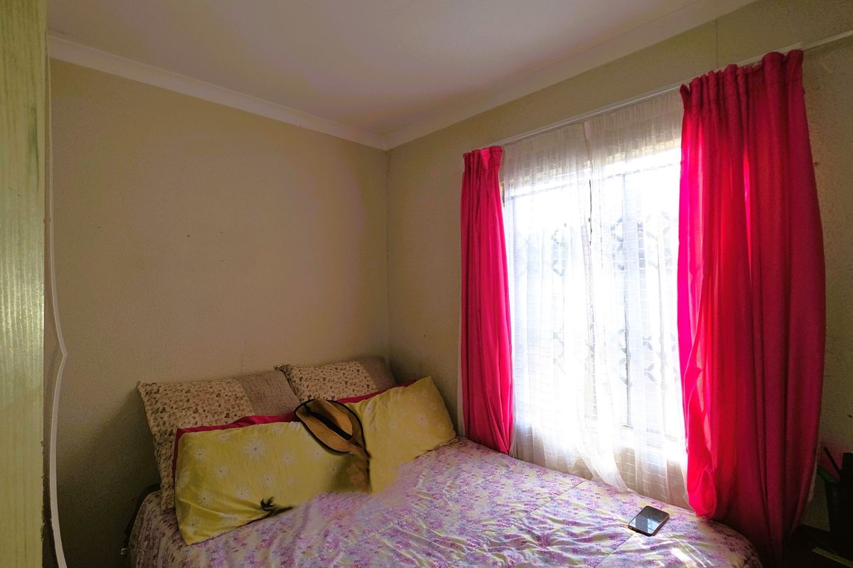 A standard bedroom featuring neutral wall finishes and a window with curtain tracks.