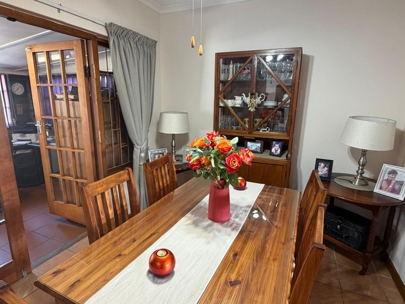 A traditional dining room featuring tiled flooring and classic timber french doors leading to an adjacent space.