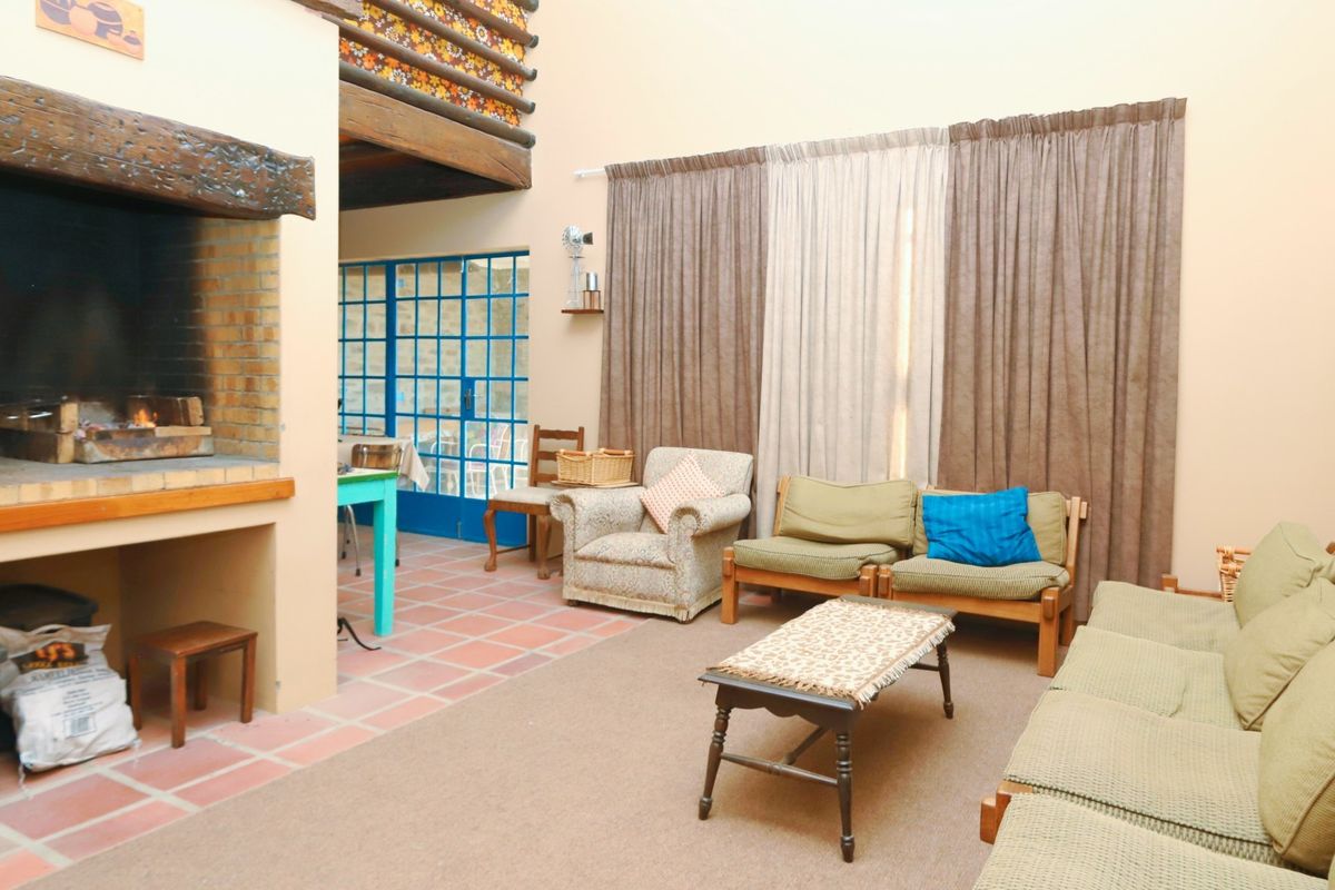 Spacious living area featuring a large built-in brick fireplace, terracotta tiled flooring, and double-volume ceilings with a mezzanine level.