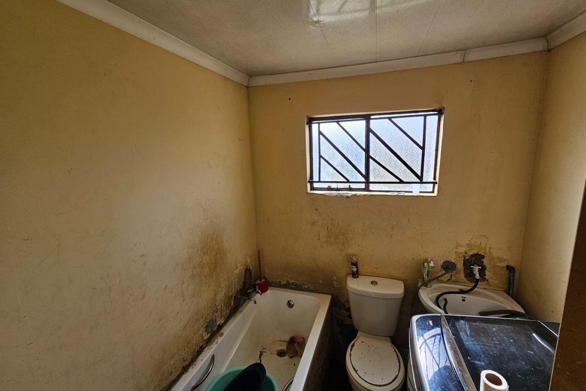 A dated bathroom featuring a bathtub, toilet, and basin, requiring significant renovation and cosmetic repairs to restore functionality and aesthetic appeal.