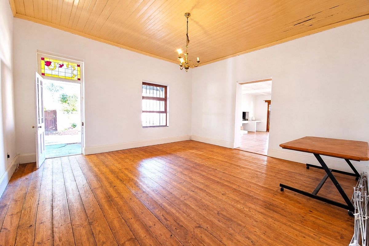 Spacious living area featuring original timber floorboards, a high timber tongue and groove ceiling, and a charming stained glass transom window above the door.