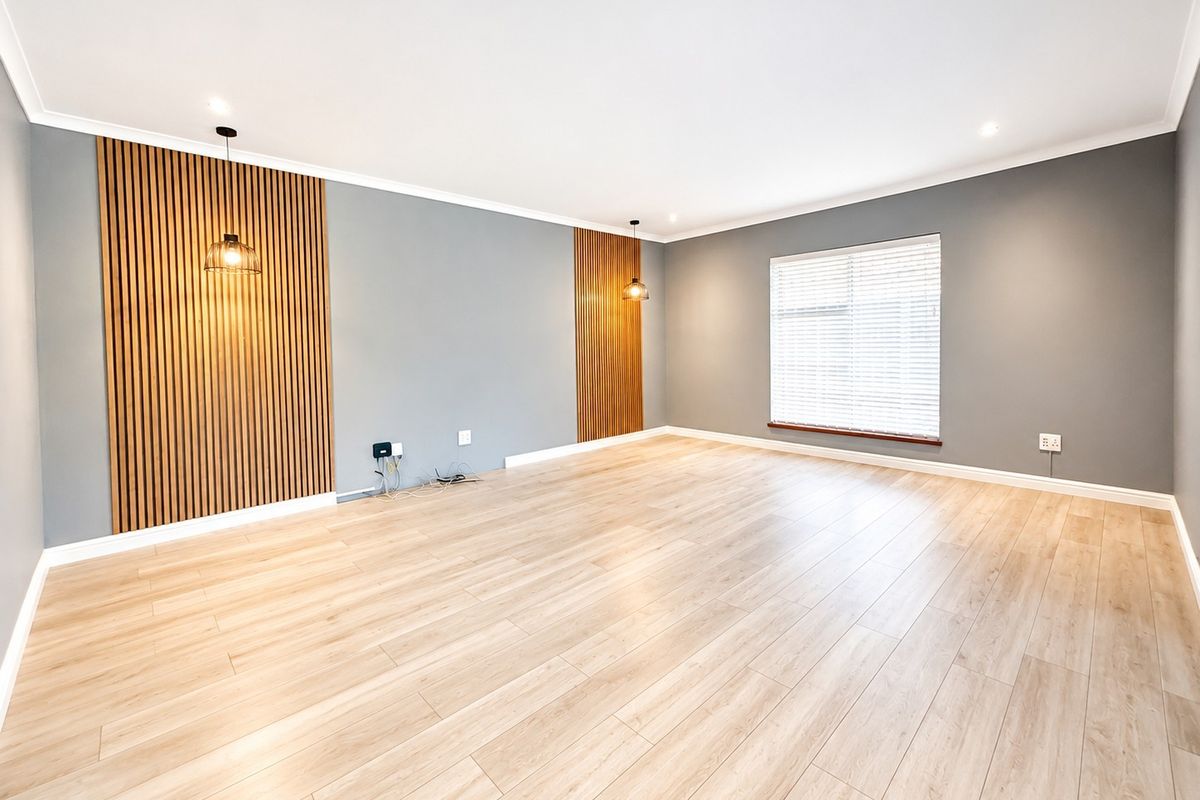 A bright and spacious living room featuring modern timber slat wall paneling, light wood-look laminate flooring, and recessed downlighting.