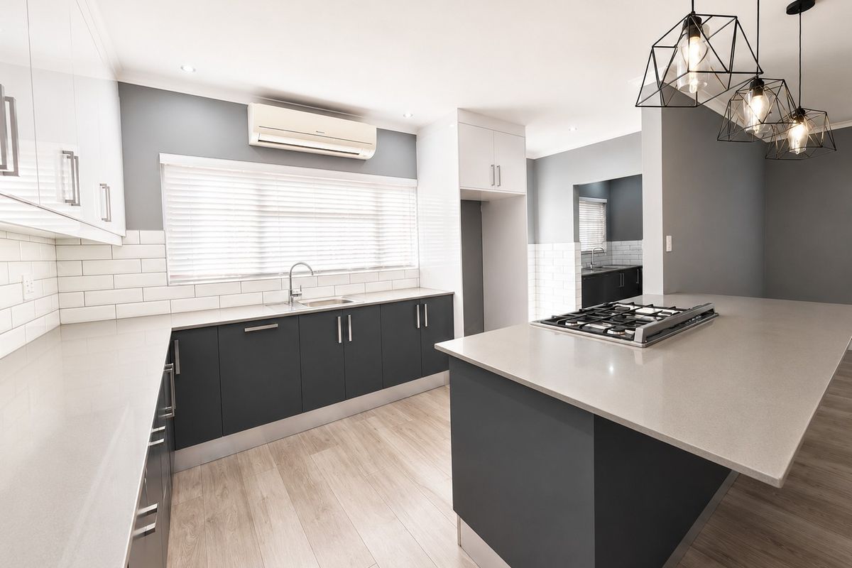 Modern kitchen featuring a central island with a built-in gas cooktop, sleek cabinetry, stone countertops, subway tile backsplash, and an integrated scullery area.
