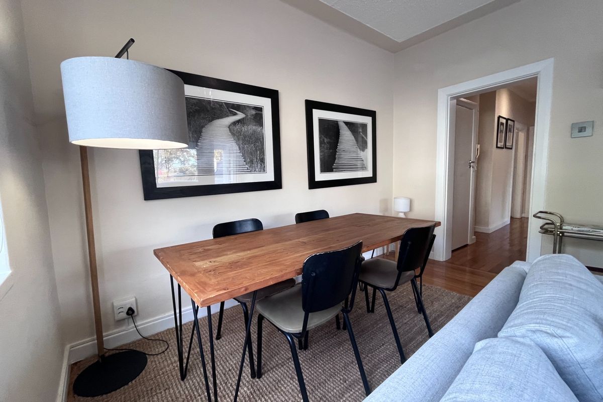 A well-maintained living area featuring hardwood flooring and neutral wall finishes, providing a comfortable and inviting space with access to the hallway.