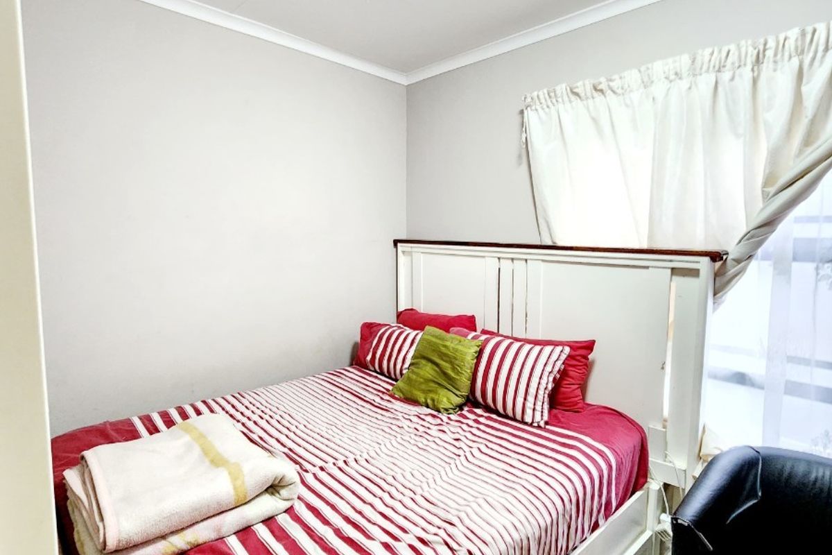 A compact bedroom featuring tiled flooring and neutral wall finishes, providing a functional sleeping space.