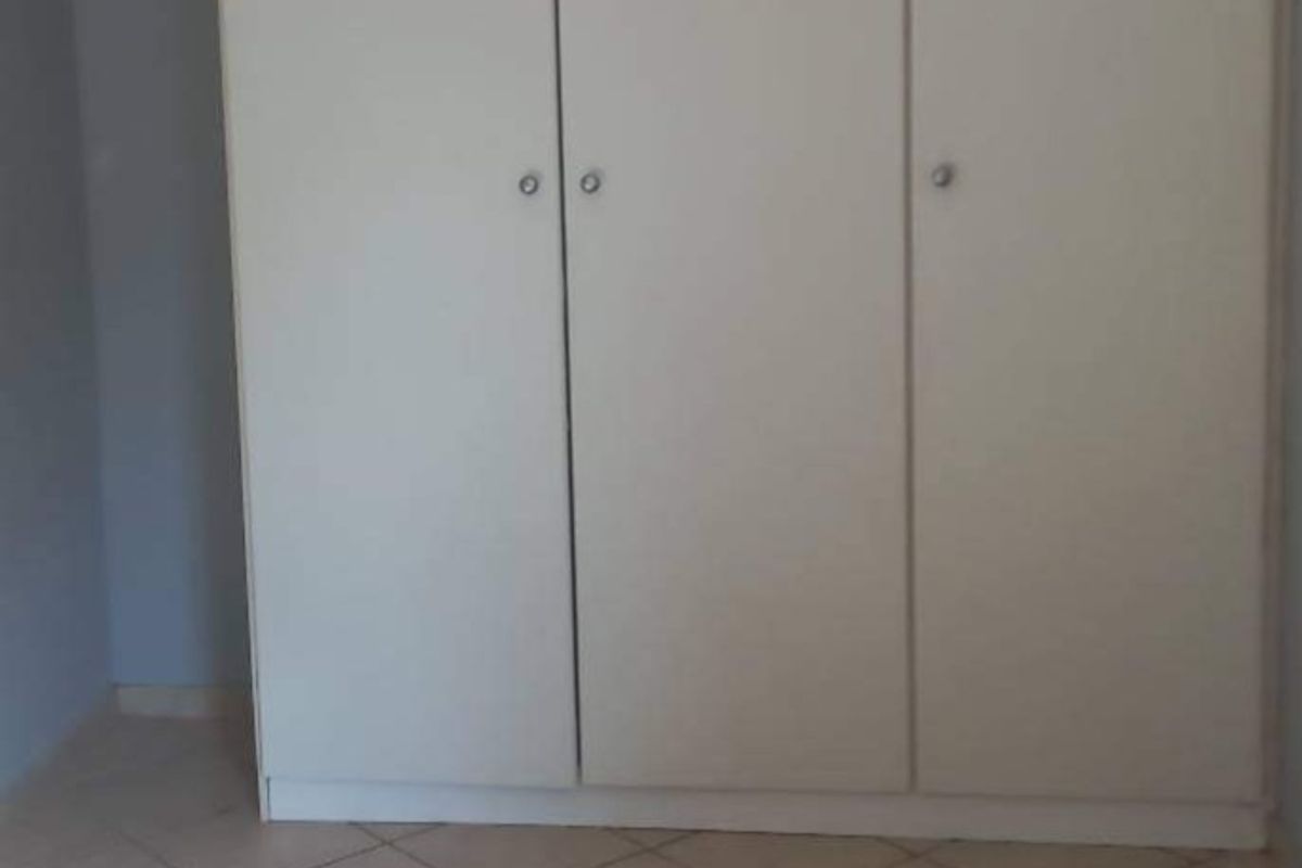 A bedroom featuring built-in cupboards with white doors and tiled flooring.