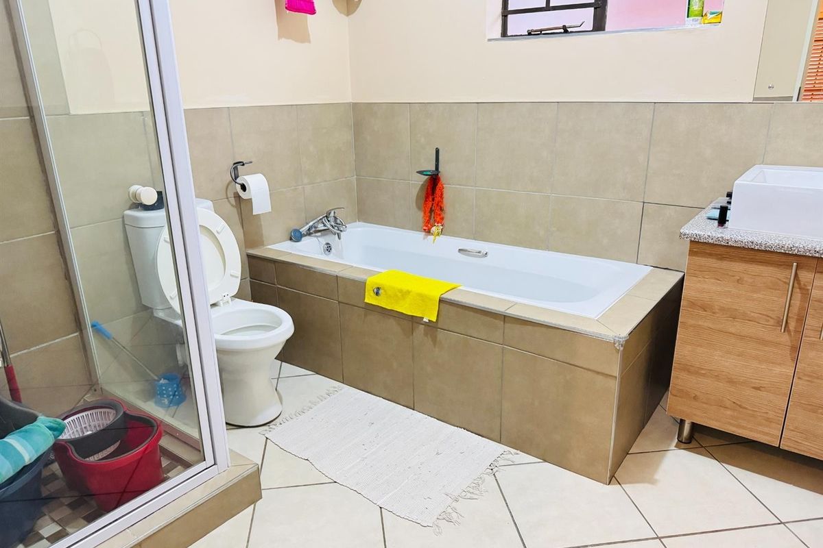 A functional bathroom featuring a tiled bathtub, a separate glass-enclosed shower, a toilet, and a modern vanity cabinet with a countertop basin.