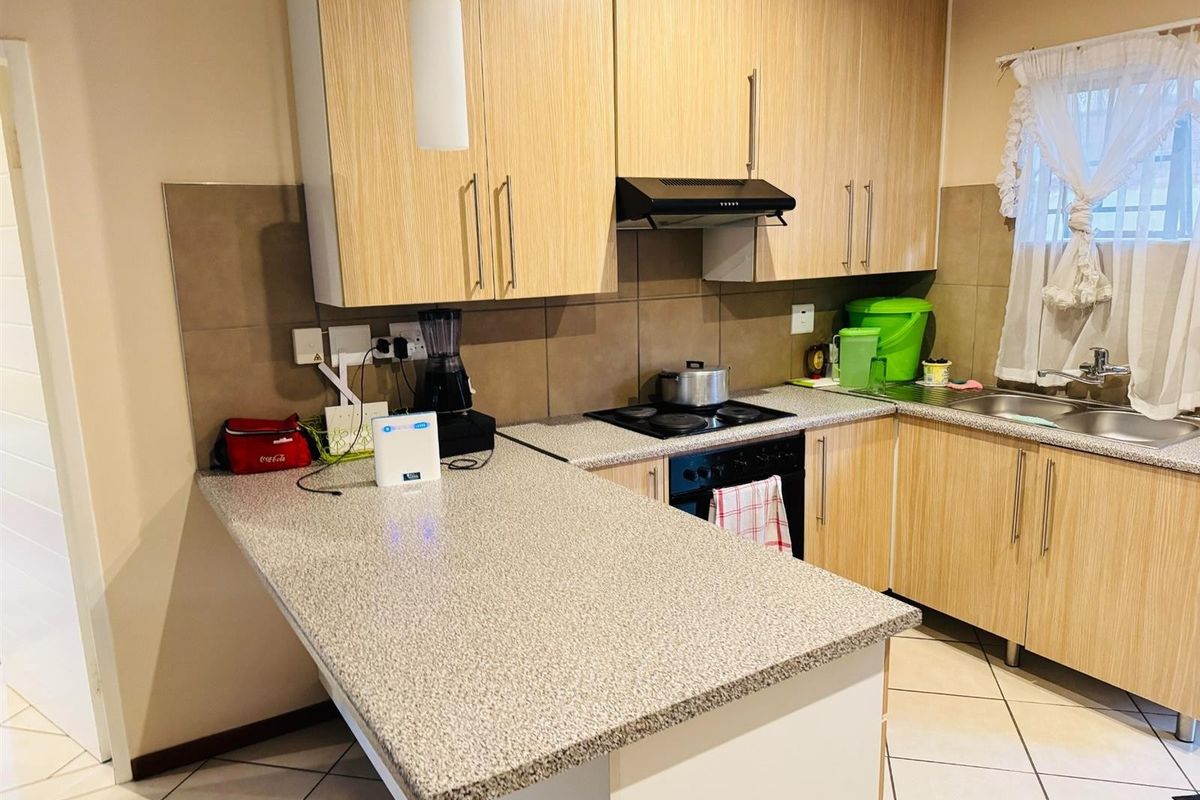 Functional kitchen featuring light wood-finish cabinetry, granite-look countertops, a built-in hob, extractor fan, and tiled flooring.
