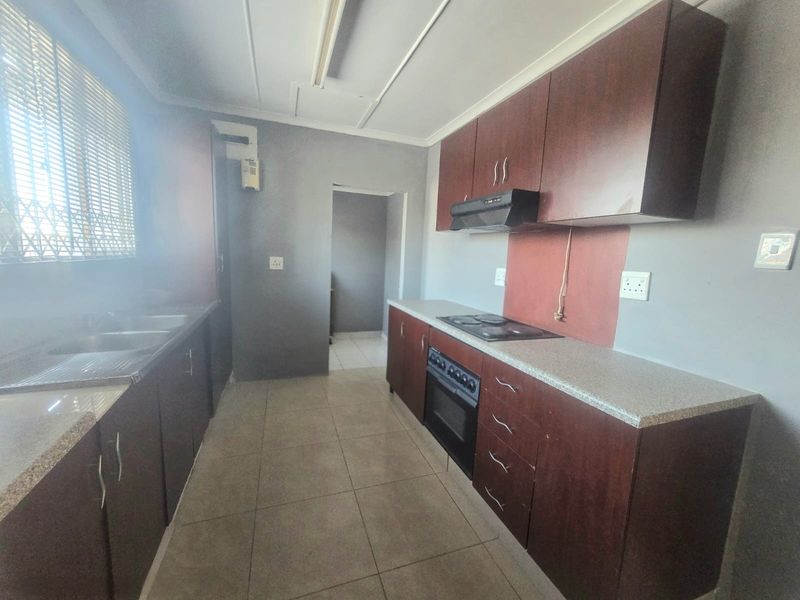 A functional kitchen featuring dark wood cabinetry, stone-look countertops, a built-in oven, and a hob with an extractor fan.