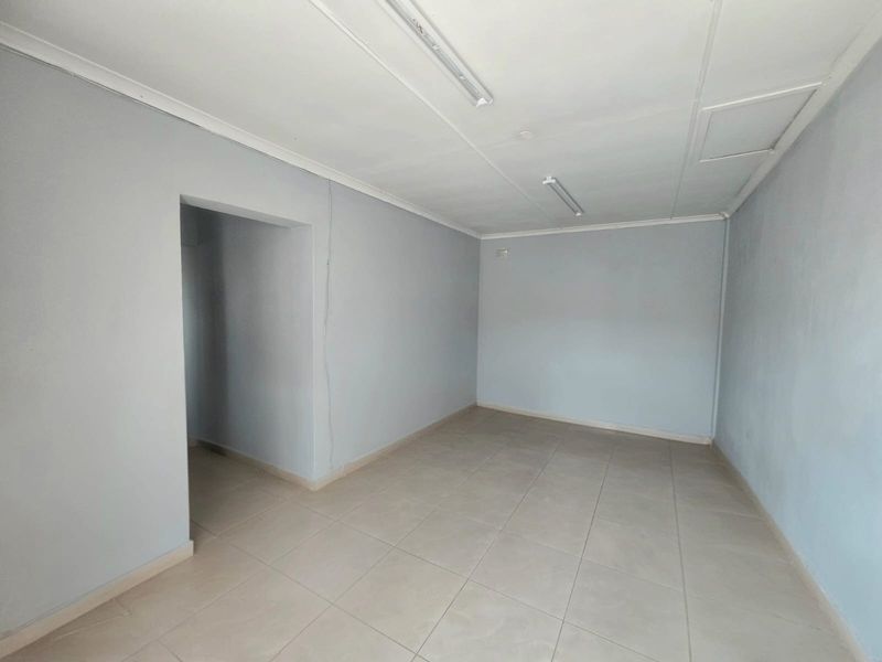 A vacant, neutral-toned room featuring tiled flooring and simple ceiling-mounted lighting, offering a blank canvas for potential living or bedroom use.