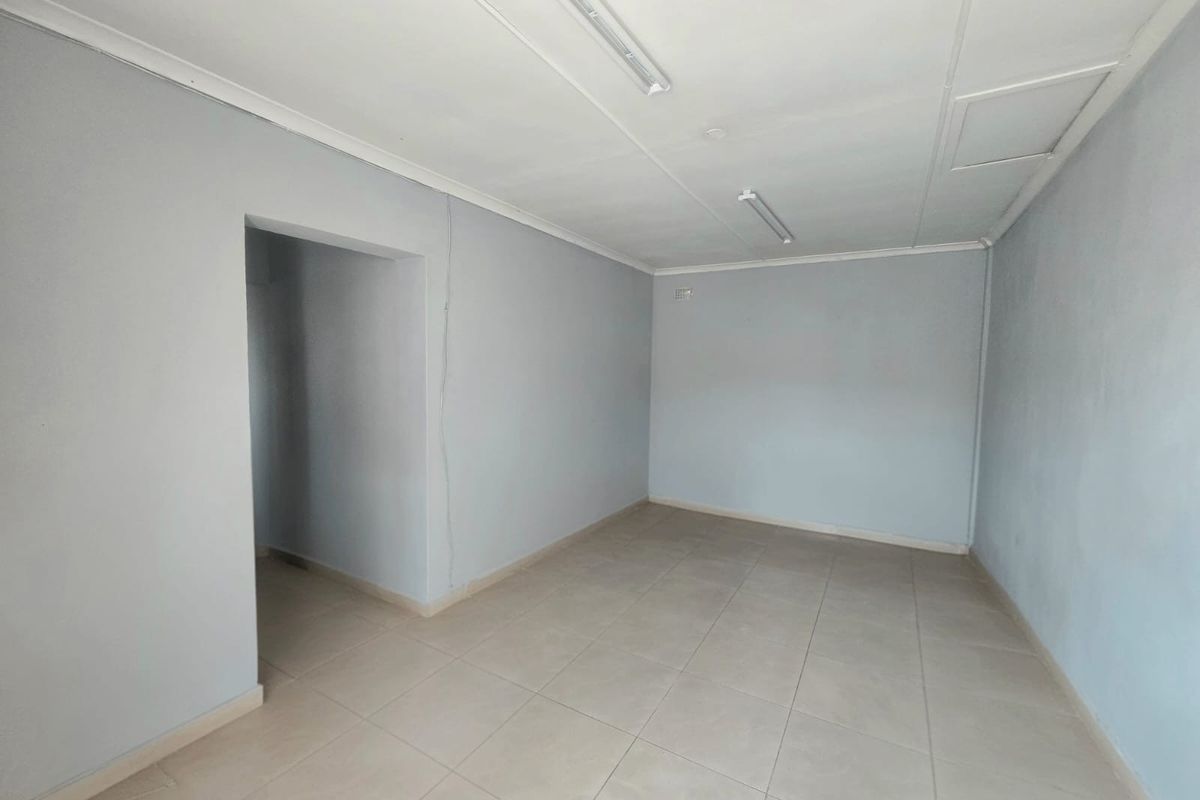 A vacant, neutral-toned room featuring tiled flooring and simple ceiling-mounted lighting, offering a blank canvas for potential living or bedroom use.