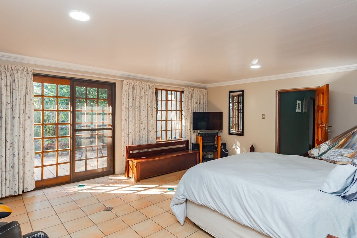 Spacious bedroom featuring tiled flooring, built-in wooden cabinetry, and sliding glass doors providing direct access to the outdoor patio area.