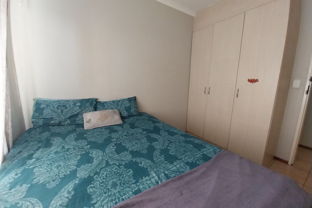 A bedroom featuring built-in light wood-finish wardrobes and tiled flooring, providing functional storage space.