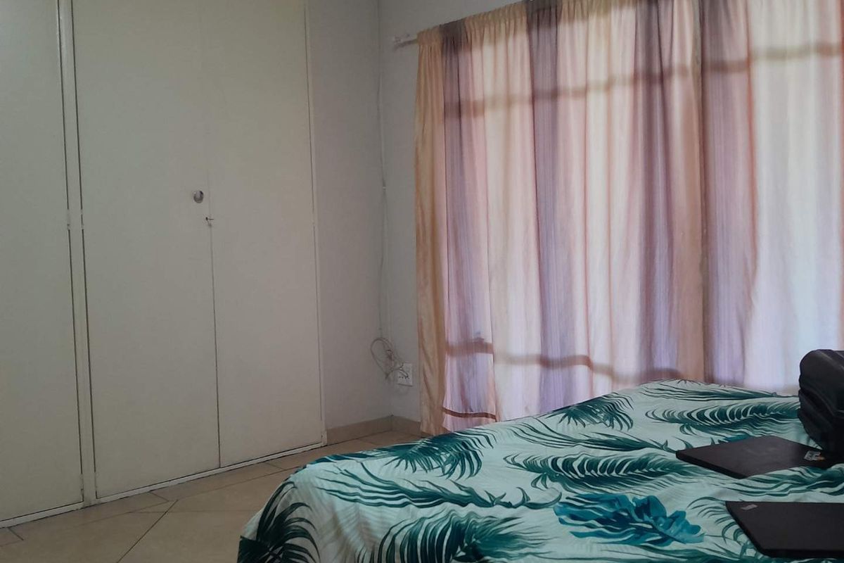 A bedroom featuring built-in cupboards and tiled flooring, providing a functional and neutral space.