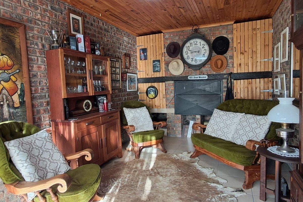 A rustic living room featuring exposed brick walls, a timber-clad ceiling, and a built-in fireplace, creating a cozy and traditional atmosphere.