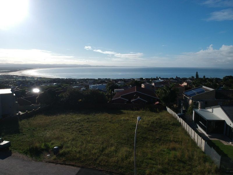 An elevated aerial view of a vacant residential plot featuring coastal and ocean views in the distance.