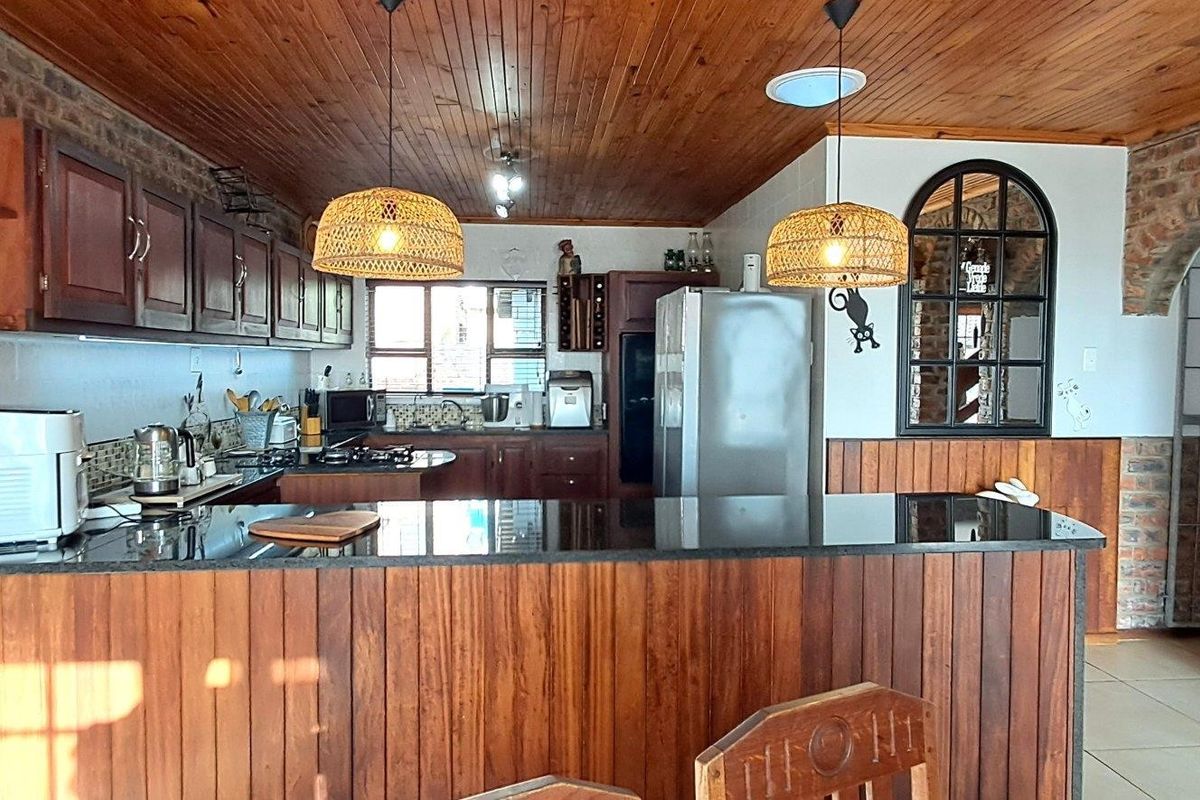 A rustic-style kitchen featuring timber ceilings, exposed brick walls, granite countertops, and wooden cabinetry, offering a warm and traditional aesthetic.